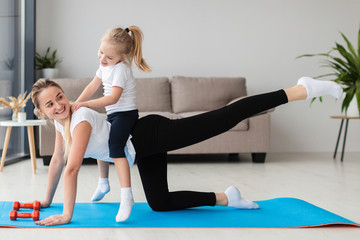 Smiling mother exercising at home with daughter