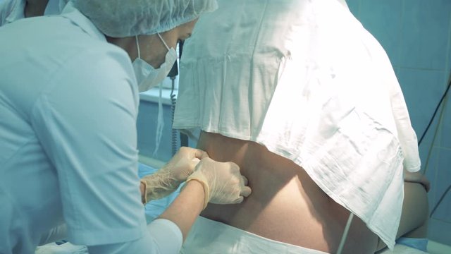 A woman is getting an injection into her lower back