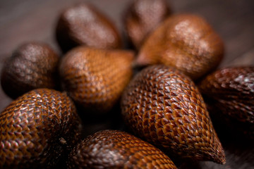 Exotic tropical salak fruit also known as snake fruit. Close-up shot of the snake fruit on brown background.