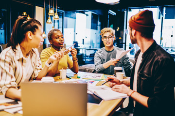 Clever young male and female multiracial hipster students sitting together in coworking space creating project in college, diverse team of employees share ideas for business startup on brainstorming