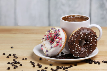White coffee cup on a wooden table with chocolate and white chocolate donuts . Morning espresso. Morning cappuccino mug. 