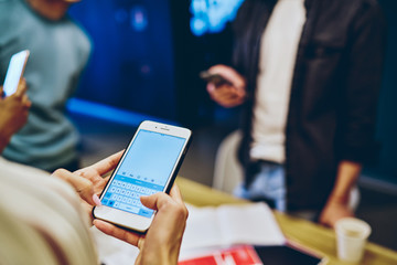 Cropped image of woman millennial using application on mobile phone for research and online booking, female holding modern smartphone typing text messages and mails communicating via 4G at work space