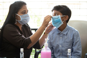 Mother instructing son how to wear a face mask and prevent self from infectious coronavirus disease