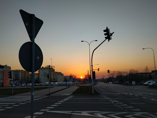 Bialystok / Poland - 08.04.2020: Fiery color sunset over the city, intersection, road signs, traffic lights, buildings, cars, empty streets without people due to isolation against coronavirus