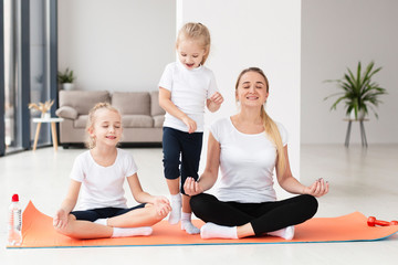 Front view of mother and daughters practicing yoga at home