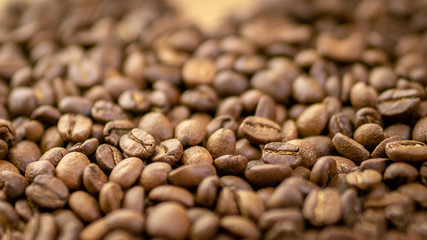 Roasted coffee beans randomly dumped on a wooden table-Close up