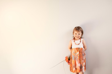 Little girl in a beautiful summer dress holding bouquet of flower red tulips behind the back, on a...