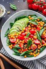 Fresh healthy salad with chickpea, avocado, cherry tomatoes and spinach.