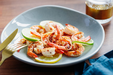 Fried tiger shrimp with lime, lemon and spices on a ceramic dish. Healthy dinner or lunch concept.