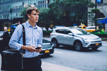 Male employee holding phone walking next  to road