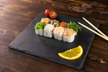 Rolls with a cap of seaweed, red caviar, shiitake mushrooms, shrimp, mussels in sauce