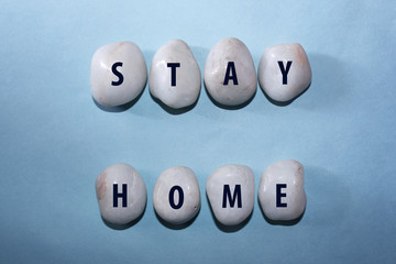 Concept Coronavirus. stay home as a text with letters on white royal sapphire rock pebbles, template against a blue background

