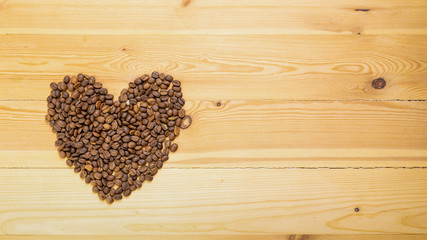 Roasted coffee beans shaped like hearts on a wooden table