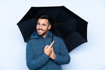 Man holding an umbrella over isolated background and pointing it