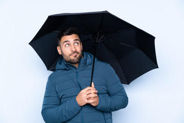 Man holding an umbrella over isolated background with sad expression