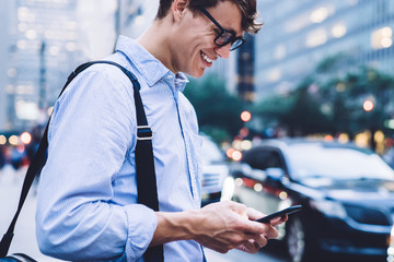 Man in shirt and glasses messaging on phone smiling outdoors