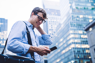 Man in eyeglasses texting on phone at street looking surprised