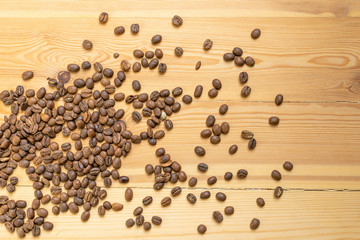 Roasted coffee beans randomly dumped on a wooden table