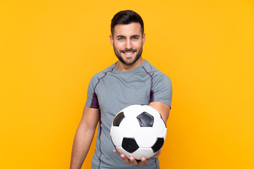 Man over isolated yellow background with soccer ball