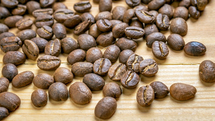 Roasted coffee beans randomly dumped on a wooden table-Close up