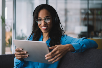 Cheerful black woman using tablet at work