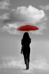 Silhouette of girl with umbrella in a dreamlike context - red umbrella with leaden sky - color contrast.