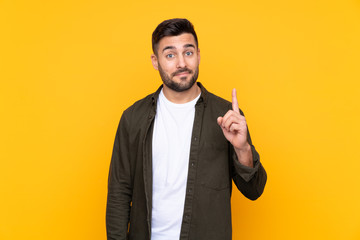 Man over isolated yellow background pointing with the index finger a great idea