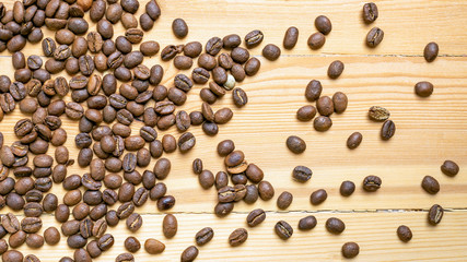 Roasted coffee beans randomly dumped on a wooden table