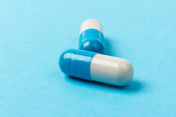 Pills isolated on blue background. Medical drug capsule. Concept of coronavirus