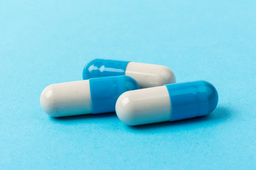 Pills isolated on blue background. Medical drug capsule. Concept of coronavirus