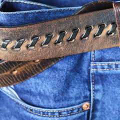 Fragment of jeans with a genuine leather belt.