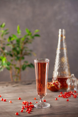 Pomegranate wine, seeds and pomegranate fruit on wooden background