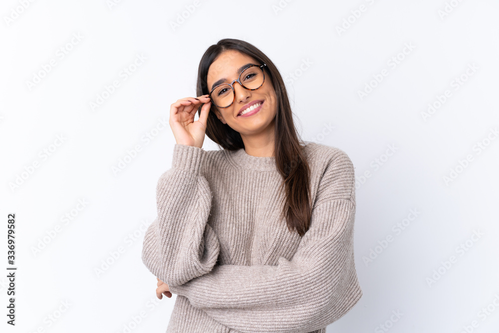 Wall mural Young brunette woman over isolated white background with glasses and happy