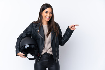 Young brunette woman with a motorcycle helmet over isolated white background surprised and pointing finger to the side