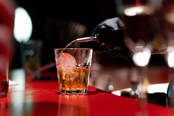 Szklanka z lodem do której wlewana jest whisky.