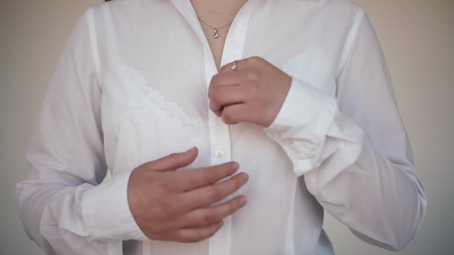 Girl unbuttoning shirt. Undress. Takes off white shirt