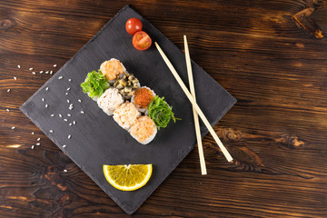 Rolls with a cap of seaweed, red caviar, shiitake mushrooms, shrimp, mussels in sauce, top view