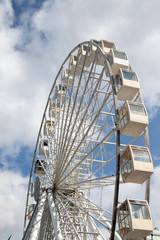 Ferris wheel in an amusement park against a on white and blue sky