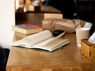 Notebook beside coffee cup on wood table in cafe