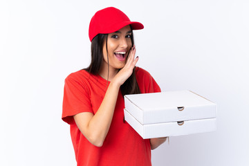 Pizza delivery woman holding a pizza over isolated white wall whispering something