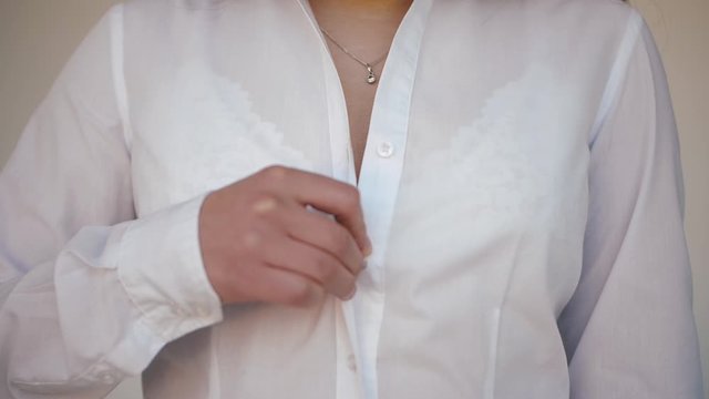 Girl unbuttoning shirt. Undress. Takes off white shirt