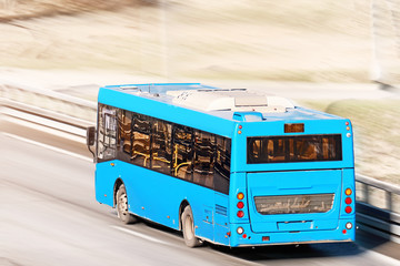 moving bus along city street against blurred background back top view of blue public transportation passenger vehicle in motion Fast driving coach on road