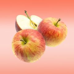 Flying red fresh whole and cut apples over pink background.