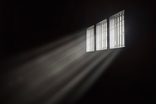 Beams of light through a barred prison cell window