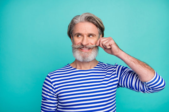 Close-up portrait of his he nice attractive cheerful grey-haired virile macho man wearing striped jumper touching mustache isolated on bright vivid shine vibrant green blue turquoise color background