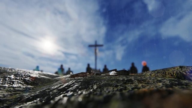 Crucifixion of Jesus Christ with thorn crown, nails, hammer and believers praying against rainy sky, 4K