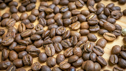 Roasted coffee beans randomly dumped on a wooden table-Close up