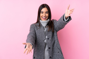 Young brunette woman over isolated pink background presenting and inviting to come with hand