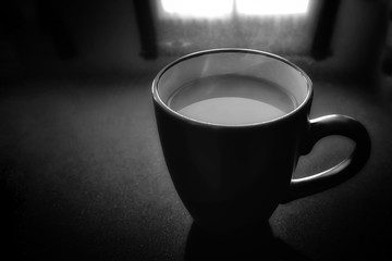 A cup of tea or coffee in black and white vintage monochrome colour with copy space on the left side.  Selective and soft focus.  Black and white photo.