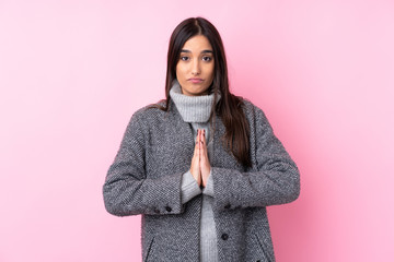 Young brunette woman over isolated pink background keeps palm together. Person asks for something